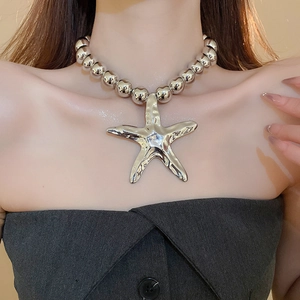 Detail of chunky silver beaded necklace featuring a large metallic starfish pendant