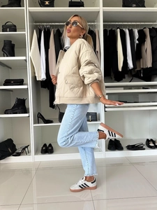 Detail of beige quilted bomber jacket with stand collar and ribbed cuffs in closet