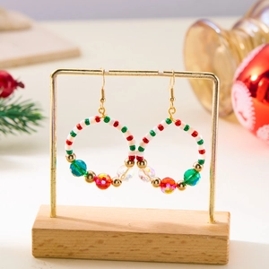 Detailed view of Christmas beaded hoop earrings with crystals on a festive gold stand