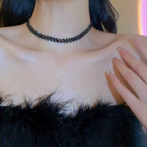 Close-up of black multilayer rhinestone choker necklace worn by a model in soft lighting