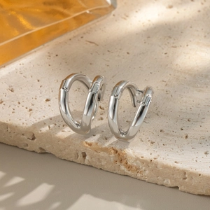 Detailed view of silver double-layered C-shaped earrings on a natural stone surface