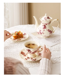 Détail de théière et tasse en céramique fleurie avec dorure dans un cadre de thé vintage