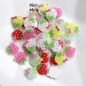 Macro shot of colorful resin strawberry charms with bows for DIY crafts and decor