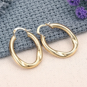Detaillierte Nahaufnahme goldener ovaler Ohrringe mit gehämmerter Metalltextur und Haken