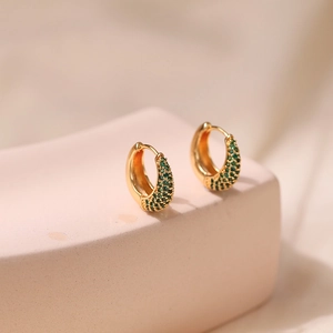 Detailed close-up of 18K gold plated U-shaped earrings with inlaid green zircons