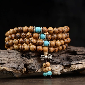 Bracelet mala en bois naturel avec perles turquoise sur un support zen en bois