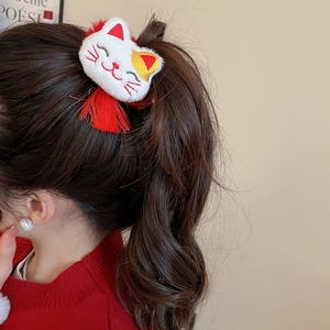 Detail of plush Maneki Neko hair tie with red tassels on a brown ponytail