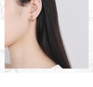 Close-up of elegant gold hoop earrings with multi-colored crystals worn by a model
