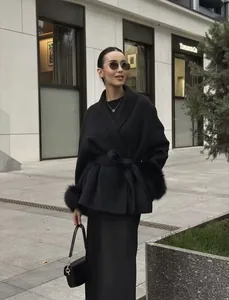 Close-up of black wool coat featuring luxurious faux fur cuffs and a waist tie detail