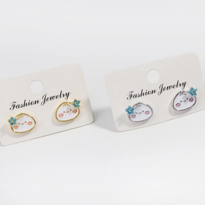 Detailed view of white cartoon bun earrings with blue flowers in gold and silver finish