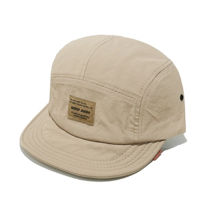 Detail of a beige five-panel camper hat showing fabric texture and woven patch