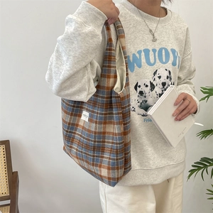 Detail view of vintage plaid tote bag with colorful checks and minimalist side woven label