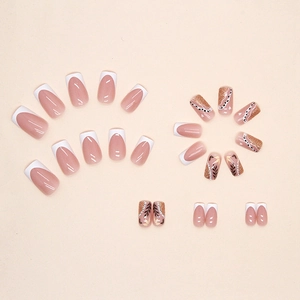 White French press-on nails with golden glitter and black leaf patterns in medium length