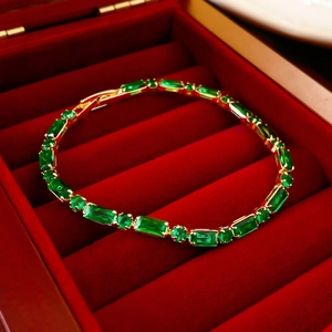 Detail of emerald green zircon gold-plated bracelet inside a red velvet jewelry box
