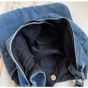 Interior view of denim tote bag featuring black fabric lining and functional zip pocket
