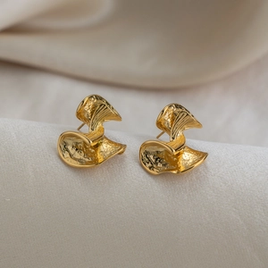 Vue macro de boucles d'oreilles en acier doré 18K avec texture éventail martelée