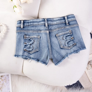 Dettaglio di pantaloncini di denim con orlo sfrangiato e tasche sul retro su sfondo tenue