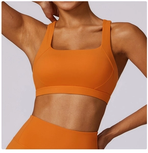 Dettaglio del reggiseno sportivo arancione con scollo quadrato sul modello fitness