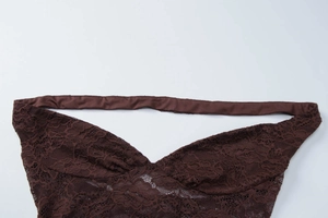 Detailed view of dark brown lace fabric with mesh floral texture and elastic strap detail
