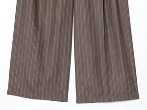 Gros plan détaillé du pantalon marron à fines rayures montrant la texture du tissu et l'ourlet