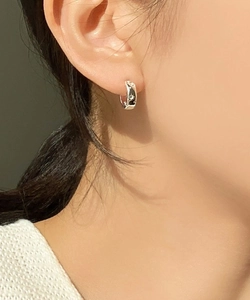 Close-up of star-etched sterling silver hoop earrings worn by a model for a daily look