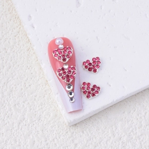 Macro view of alloy heart nail charms with pink rhinestones and crystals set on nails