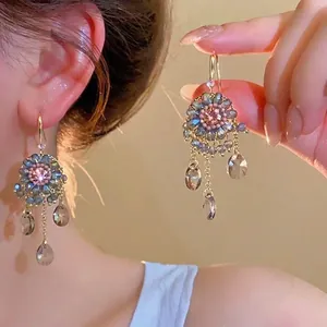 Detailed view of pink floral crystal tassel earrings worn on ear with drop pendants