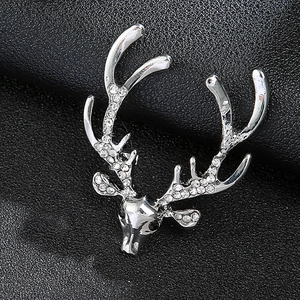 Macro shot of silver reindeer brooch with sparkling rhinestones on black leather texture