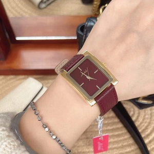 Close-up of rectangular wine red dial and leather strap watch on a woman's wrist