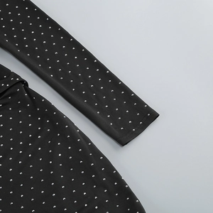 Detail of silver rivets on black slim-fit knit dress with high-quality rhinestone finish