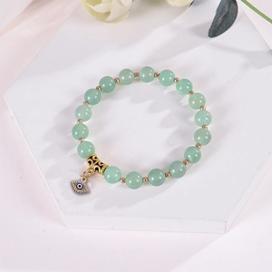 Detail of 8mm pink zebra stone bracelet with evil eye charm on white geometric stand
