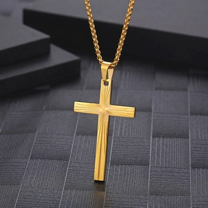 Macro shot of golden cross pendant with sunburst texture on black geometric background