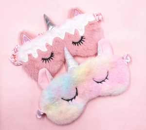 Detail of plush unicorn sleep masks with glitter horns and gradient rainbow fur textures