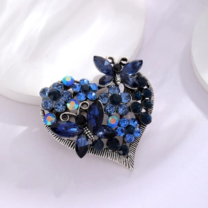 Makroaufnahme der Vintage-Herz-Brosche mit blauen Kristallen und Schmetterling