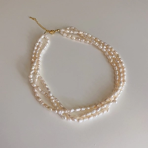 Close-up of triple-layered freshwater pearl necklace with adjustable gold clasp