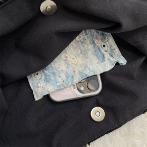Detail of black canvas tote showing blue floral embroidery pocket and magnetic snap closure