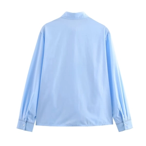 Vue arrière d'un chemisier bleu clair à manches longues avec poignets boutonnés sur blanc