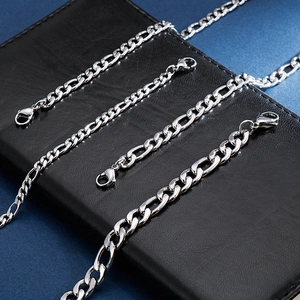 Close-up of stainless steel Figaro chains with lobster clasp on a leather texture
