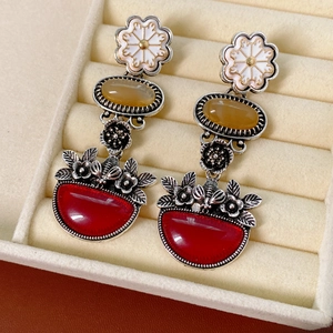 Detail of vintage floral drop earrings with red and amber stones in a velvet jewelry box