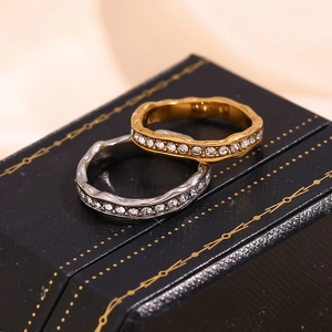 Detailed macro of gold and silver wave rings with inlaid crystals on a black box