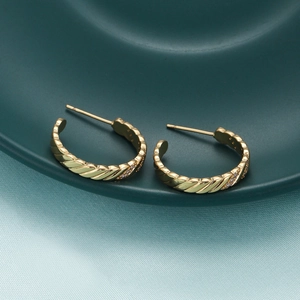 Detailed view of 18K gold plated twisted hoop earrings with sparkling zircon accents