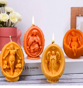Details religiöser Osterkerzen mit Relief-Motiven von Jesus und Maria in Orange