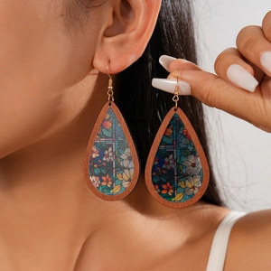 Detail of bohemian teardrop earrings with wood frame and floral acrylic inlay on a model