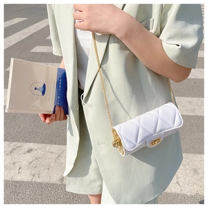 Chic white quilted cylinder bag with gold chain strap on a model in sunlight