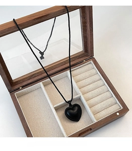 Détail d'un collier pendentif cœur noir placé dans une boîte à bijoux en bois chic