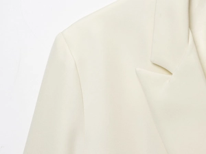 Détail du revers d'un blazer croisé blanc avec texture de tissu tissé de qualité