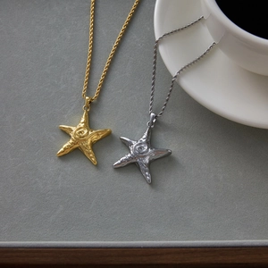 Detailed close-up of gold and silver starfish pendants with textured spiral design