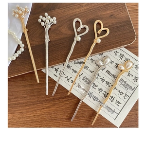 Detail of 6-piece metal hair sticks set with white pearls on vintage wood and calligraphy