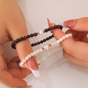 Stackable gold beaded bracelets with natural pearls and purple beads on hand