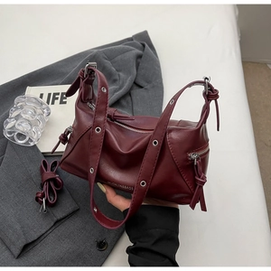 Detail view of wine red tote with silver grommets and tassel zipper on a blazer